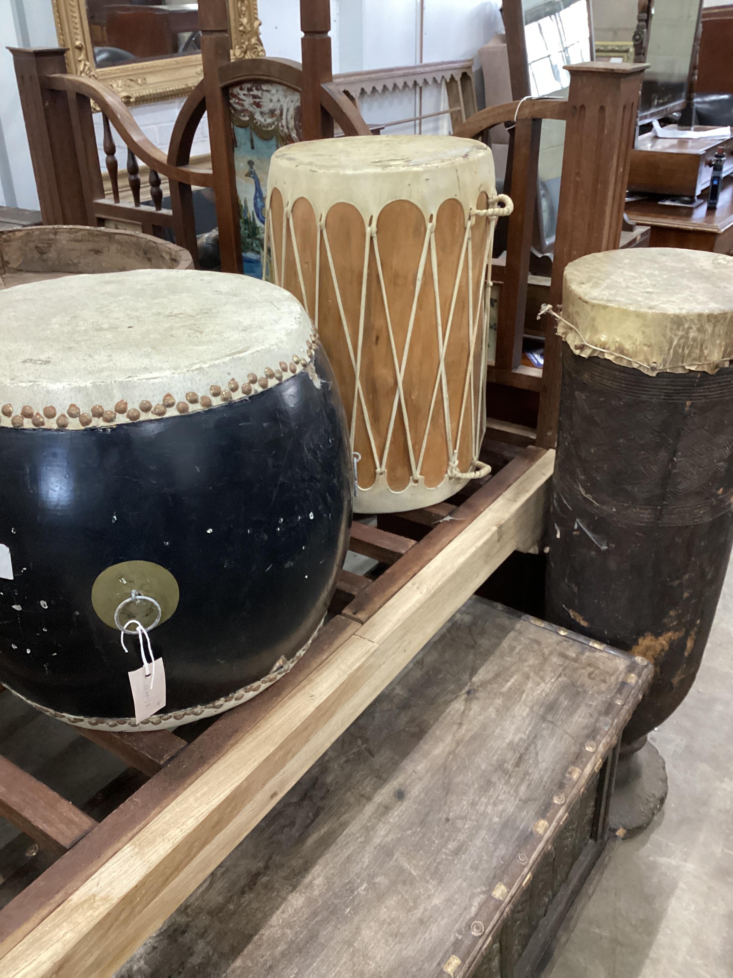 Three African and Chinese hardwood and hide drums, largest height 104cm